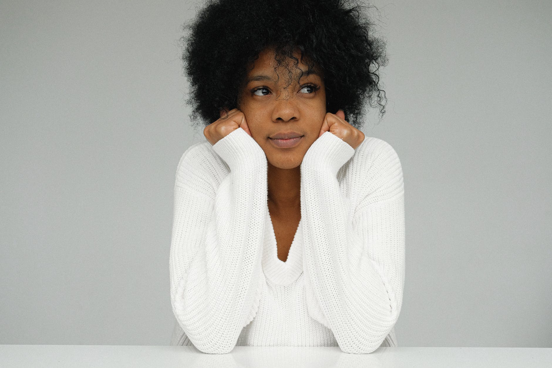 portrait of a woman in white sweater holding her chin